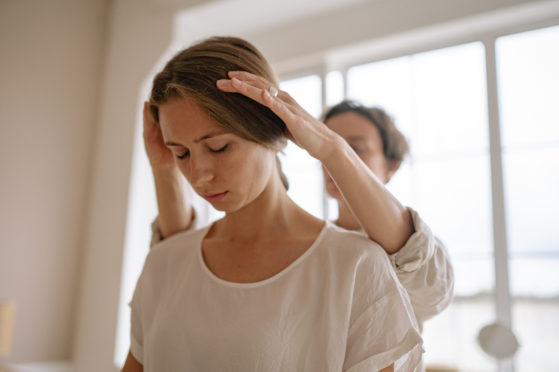 Person in White Long Sleeve Shirt Massaging Woman's Head
